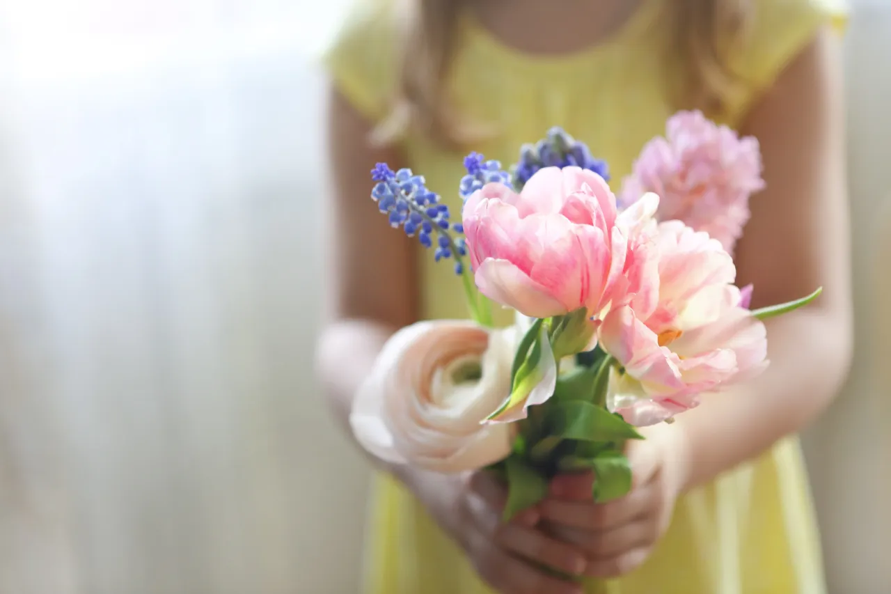 Flicka håller en bukett med blommor. 